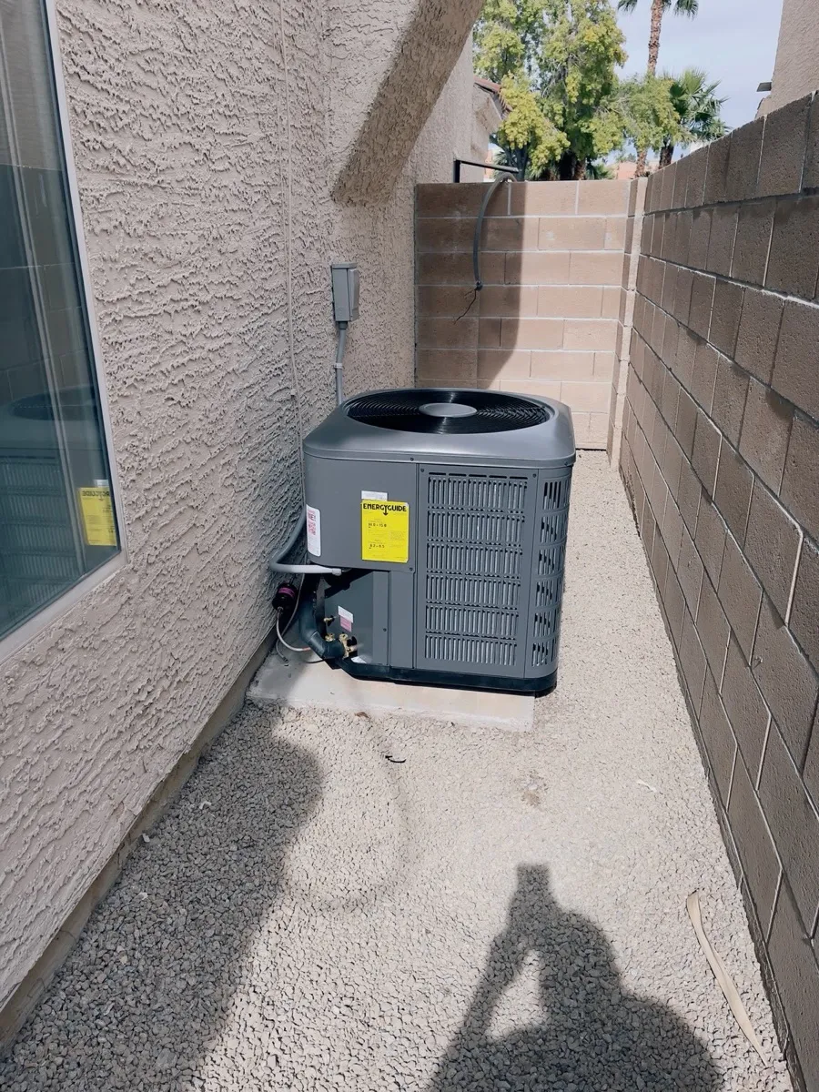 New condenser installed in a Las Vegas side yard with palm trees behind the block wall