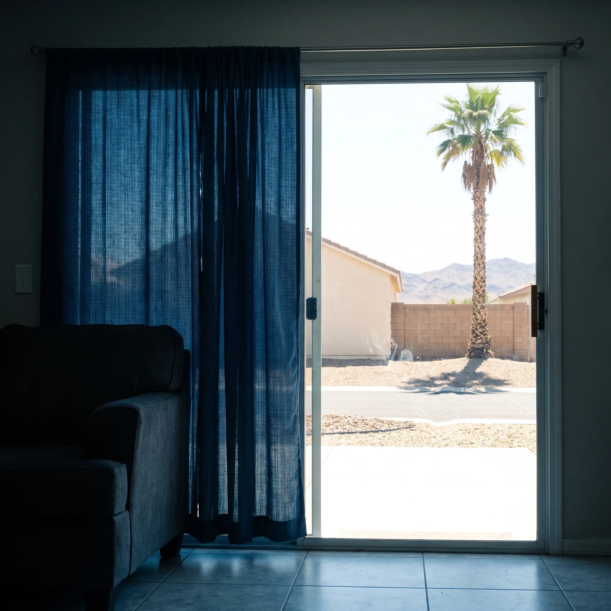 View from inside a cool, shaded Las Vegas living room out through a sliding door to a blazing desert afternoon